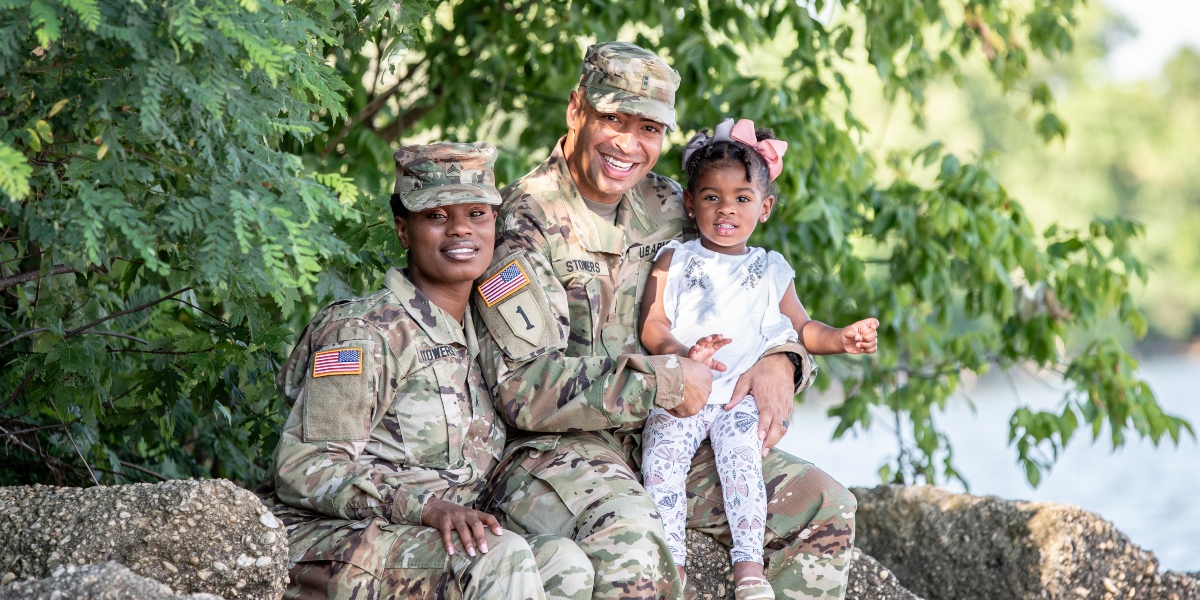 Military family sitting near a picturesque lake.